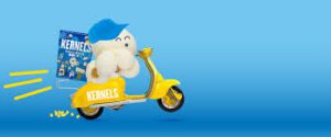 A kernel popcorn riding a yellow bike wearing a blue baseball cap